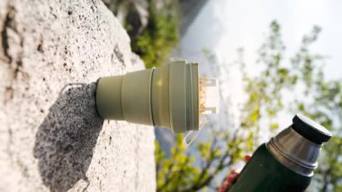 Drip Coffee Bag in a Cup 'ın dikey videosu. Yaz bahçesinde termostan gelen sıcak suyla demlenen içeceğin süreci.