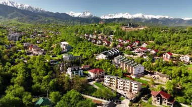 Hava aracı manzaralı evler yeşil tepe vadisi manzaralı kar dağları mavi gökyüzü manzaralı Kazakistan, Almaty şehrinde