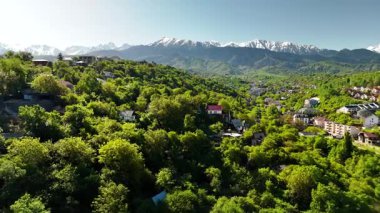 Hava aracı manzaralı evler yeşil tepe vadisi manzaralı kar dağları mavi gökyüzü manzaralı Kazakistan, Almaty şehrinde