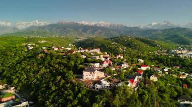Hava aracı manzaralı evler yeşil tepe vadisi manzaralı kar dağları mavi gökyüzü manzaralı Kazakistan, Almaty şehrinde