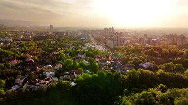 Hava aracı manzaralı geniş yol manzaralı trafik ve evler, otel, günbatımında gökyüzü arka planında binalar Almaty City, Kazakistan