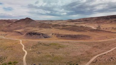 Aerial view Drone shot dusty country road near river Ili and spring steppe at sunset cloudy sky in Kazakhstan