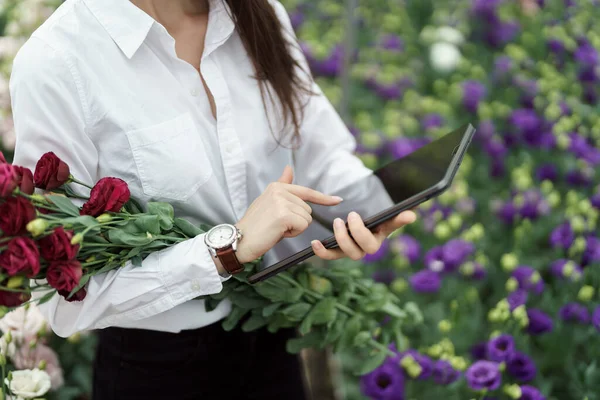 Fresh flowers delivery, women taking order on the tablet. Businesswoman using technologies in her flower business.