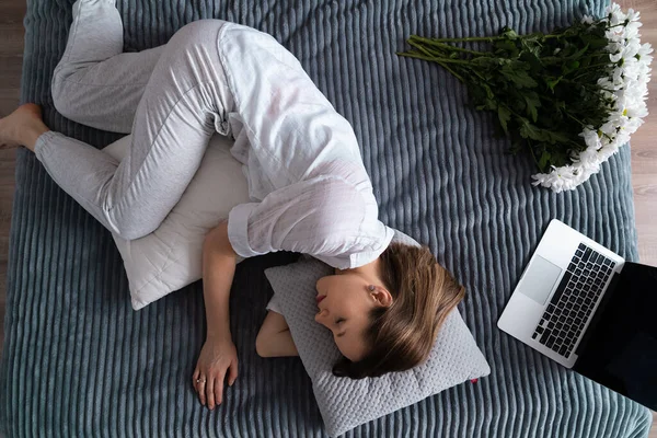 白いカジュアルな服を着た白人女性はベッドの上でラップトップを使用している間に眠ってしまいました — ストック写真