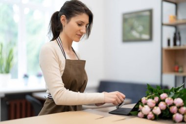Kadın, dükkanda çalışırken hediye kutusuna pul yapıştırıyor. Sipariş için hazırlanın.