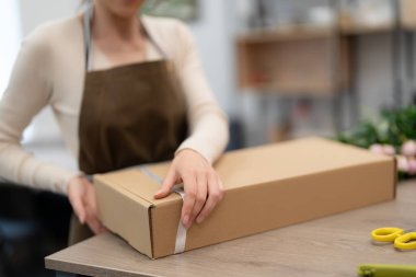 Çiçeklerle atölyesinde çalışan bir kadın sipariş üzerine kompozisyon kutusu yapıyor.