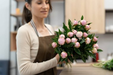 Çiçeklerle çalışan çiçekçi kadın atölyesinde beste yapıyor.