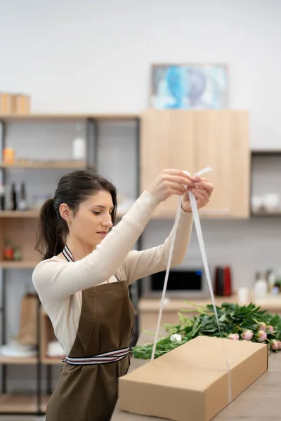 Woman Florist working in her workshop with flowers making a composition box on order