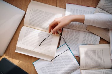 Young women got asleep on the books while studying holding reading glasses