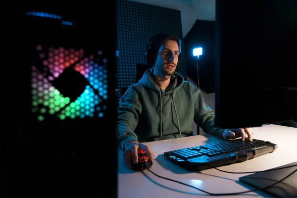 ヘッドセットを着用し ネオンライトで照らされた暗い部屋での戦いを持つビデオゲームをプレイしている集中男性サイバースポーツゲーマー — ストック写真