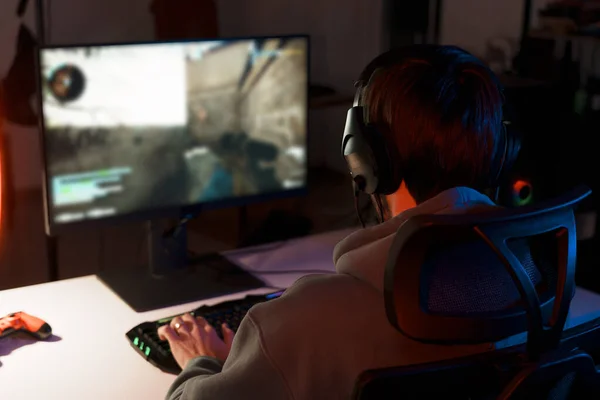 Gamer transmitindo o jogo de tiro em primeira pessoa enquanto explica a  jogabilidade aos assinantes enquanto está sentado na cadeira de jogos.  homem usando a configuração do pc jogando jogo de ação