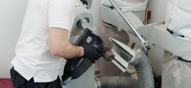 Modern atölyedeki zımparalama makinesinde şekillendirme ve şekillendirme yaparken protez uzuv üzerinde çalışan tanınamaz hale gelmiş usta eldivenlerin yakınlaştırılması