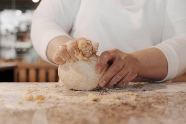 Beyaz üniformalı, hamuru yoğurup mermer tezgahta top yapan isimsiz bir kadın aşçı.