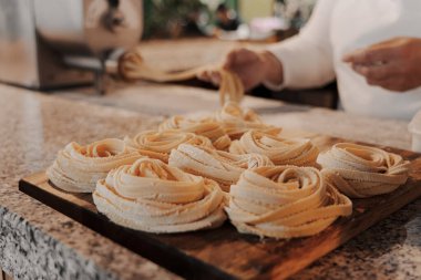 İştah açıcı el yapımı doğal tagliatelle makarna ruloları mutfakta ahşap doğrama tahtasına yerleştirilmiş.