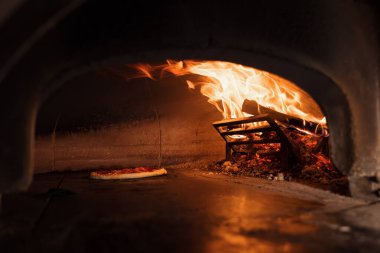 Pizza konsepti. Geleneksel İtalyan pizzasını hazırlıyorum. Pizza için uzun kürek, profesyonel bir fırında hamur pişirmek modern restoran mutfağının içinde ateş yakmak. Yüksek kalite fotoğraf