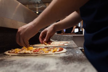 Yemek konsepti. Geleneksel İtalyan pizzasını hazırlıyorum. Modern restoran mutfağının içinde üniformalı bir şef. Yemek hazır.