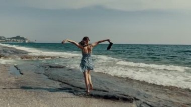 Genç kadın Akdeniz 'in kayalık kıyılarında yürüyor. Yüksek kalite 4 bin yavaş çekim görüntüsü