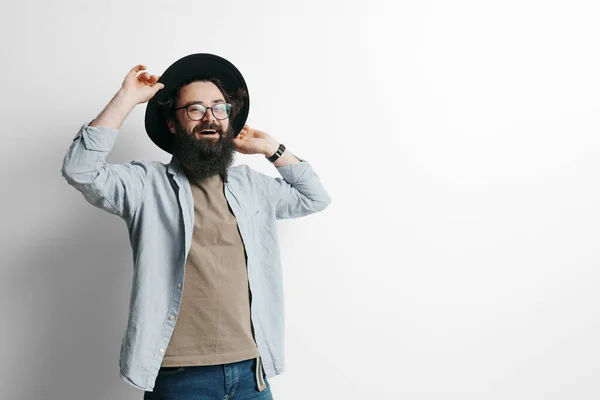 Handsome stylish man with beard on white background. Smiling man wearing black hat and glasses
