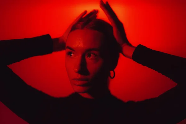 Endişeli Genç Bir Kadın Elleriyle Başını Tutuyor Kırmızı Işıklandırmalı Stüdyo — Stok fotoğraf