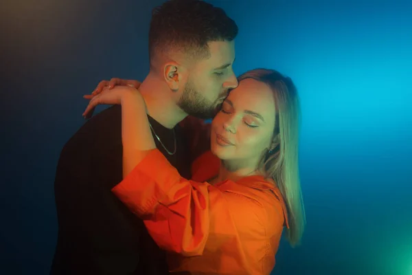 stock image Side view of young lovers embracing while standing in dark room with neon illumination