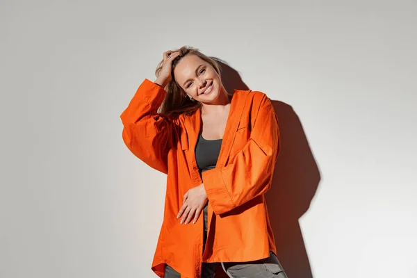 Positive Junge Blondhaarige Frau Orangefarbenem Hemd Steht Vor Weißer Wand — Stockfoto