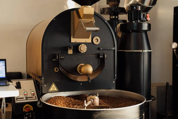 Professional machine in process of roasting and mixing coffee beans in modern industrial factory