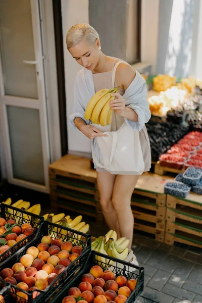 Młoda Kobieta Letnim Stroju Kupuje Świeże Owoce Chodniku Trzyma Kilka — Zdjęcie stockowe