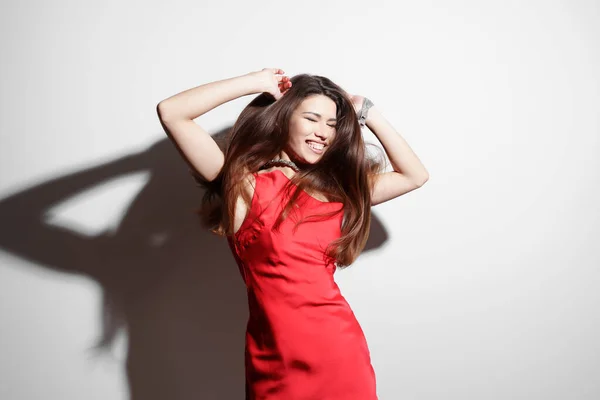 Captured in a moment of carefree joy, a woman dances in a red dress, her laughter and dynamic movement embodying the essence of playful elegance