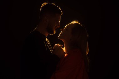 Öpüşmek üzere olan bir çiftin mahrem silueti, profillerini özetleyen yumuşak, romantik bir parıltıyla sarmalanmıştı.