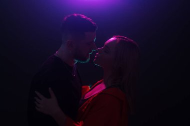 Simgeli bir çift alacakaranlık renklerinde bir arka planın altında, romantizmi çağrıştırıyor.