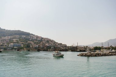 Bereketli tepeler ve berrak bir turkuaz deniz ile çevrili, kıyı sükunetini somutlaştıran bir teknesi olan sakin bir liman kasabası.