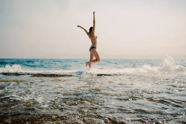 純粋な喜びの瞬間を捉え 輝く海の波の背景に女性が飛び込む — ストック写真