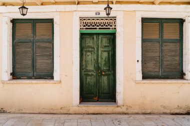 Eşleşen panjurlarla çevrili büyüleyici yeşil bir kapı Akdeniz mimari cazibesinin bir fotoğrafını sunar.