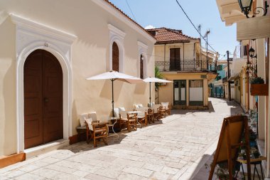 Beyaz şemsiyeli büyüleyici bir kafe, Akdeniz 'deki bir kasabanın güneşli kaldırım taşı sokağında ziyaretçileri karşılıyor.