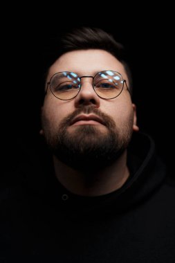 Düşünceli bir adamın yakın çekimi, yansımaları gözlüklerinin altını çiziyor.