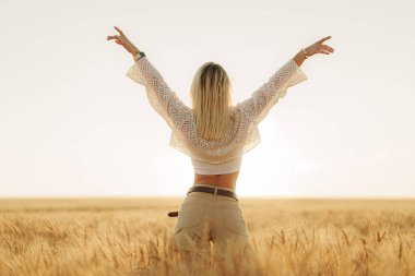 Kameraya döndü, bir kadın kollarını kaldırdı özgürlük jesti olarak, güneşli bir buğday tarlasının uçsuz bucaksız genişliğiyle karşı karşıya.