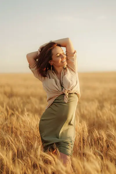 A womans carefree spirit shines as she embraces herself, surrounded by the rich glow of the wheat field at sunset