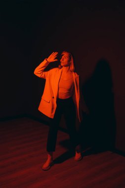 Bir model cesur bir açıklama yapar, elini koyu kırmızı bir zemine kaldırır, gölge bırakır.