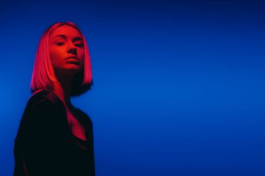 Bir kadın silueti, parlak bir neon ışıltısı içinde, koyu mavi bir arka planla gizemli ruh halini güçlendirir.