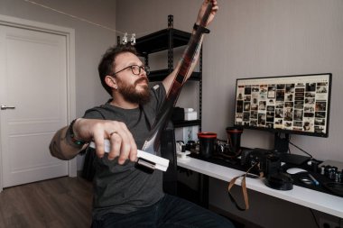 Yetişkin bir adam geleneksel film denetimine karşı modern dijital arşivleme ile bir stüdyoda fotoğrafçılığın evrimini sembolize eder.