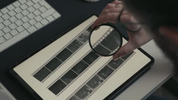 Seorang Fotografer Menggunakan Kaca Pembesar Untuk Memeriksa Secara Rinci Foto — Stok Video