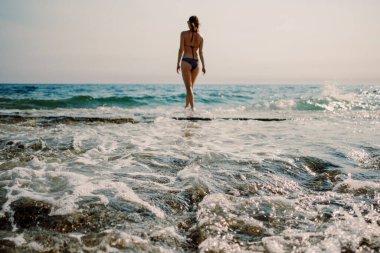 Akdeniz 'in ışıl ışıl parıldayan sularına dalmaya hazır, tek başına bir yüzücü su kenarında duruyor.