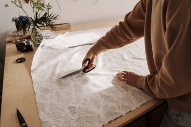 İyi ışıklandırılmış, rahat dikiş atölyesinde makaslı kadın terzilik yapıyor..