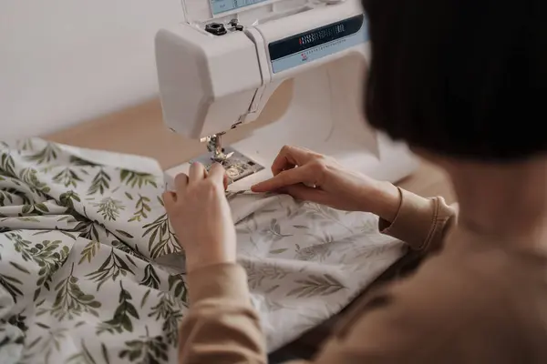 Person sewing fabric on a machine, focused craftsmanship