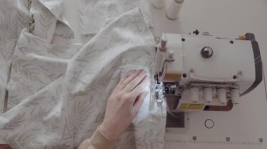 İyi aydınlatılmış bir atölyedeki dikiş makinesinde kumaşla çalışan odaklanmış bir terzi..