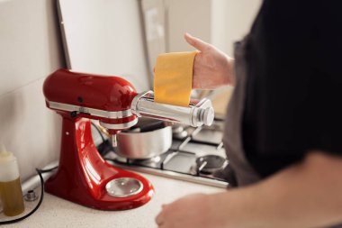 Ev yapımı erişte hazırlamak için canlı kırmızı makarna makinesi kullanan biri..