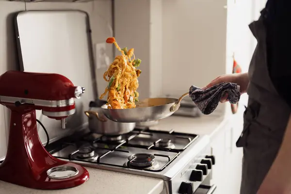 ストーブにパスタをフリッピング キッチンミキサー付きダイナミックな家庭料理シーン ストック画像