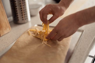 Yakın plan çekimde makarna bir mutfak tepsisine konur. Hazırlık konsepti.