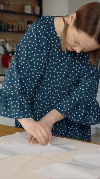 工芸プロジェクトに従事する集中女性 家庭で明るい木製のワークテーブルに布の模様を追跡し 創造性と集中力を伝える — ストック動画