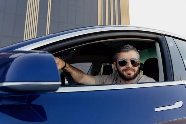 편안한 표현을 남자는 자동차를 운전합니다 선글라스를 착용하고 배경에 편안하게 보입니다 스톡 이미지